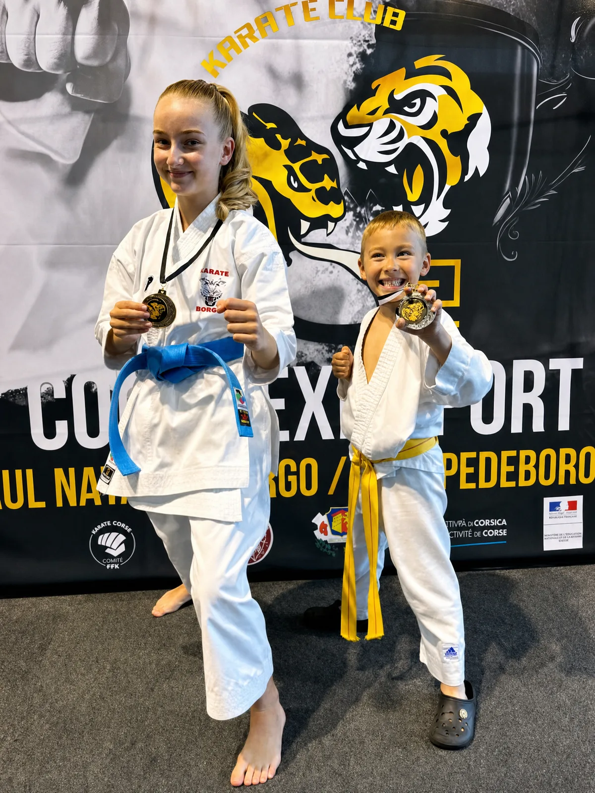 Jeunes championnes du KC Borgo souriantes avec leurs médailles devant le logo du club