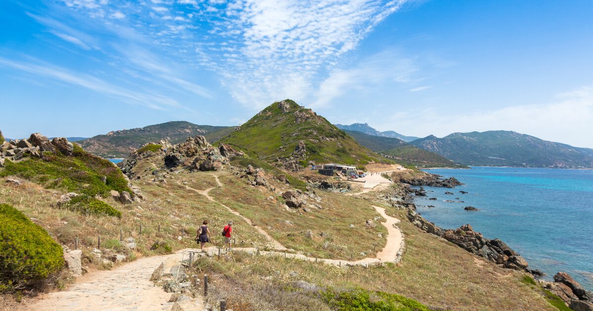 Sentier côtier des douaniers en Corse, chemin serpentant entre maquis et mer turquoise